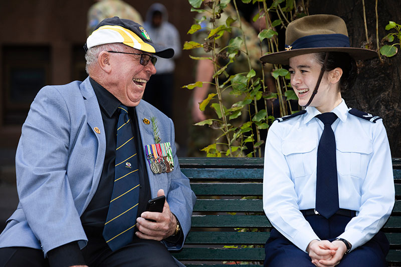 Image: Defence Australia | Veteran Dick Walter shares a story and a laugh with Cadet Corporal (AAFC) Simone Turner