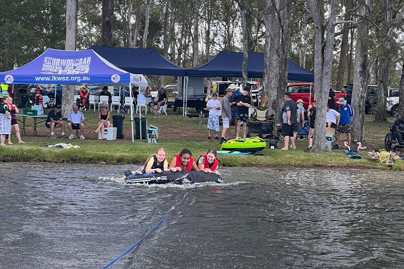  On Charity Day, after serving the barbecue, students ride the 	tubes behind a speedboat.