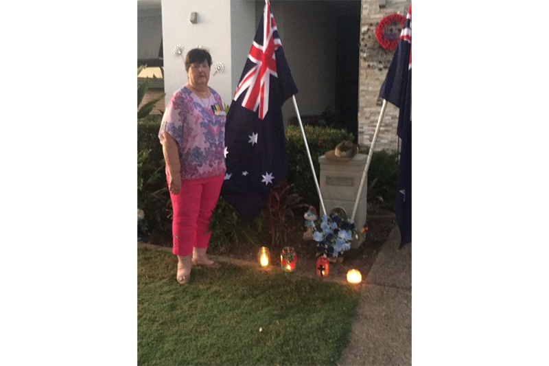 Helen Smith OAM standing next to Australian flag