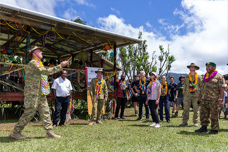 Image: Defence Australia |  Regimental Sergeant Major – Army, Warrant Officer Grant McFarlane, AO (left) spins coins into the air during a game of two-up at Efogi village on the Kokoda Track as part of the Anzac Day 2019 commemorations, Papua New Guinea.