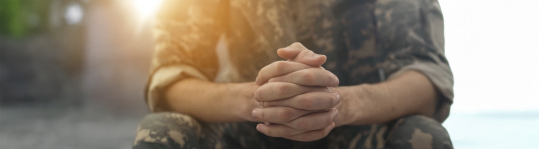 Defence personnel sitting with hands clasped
