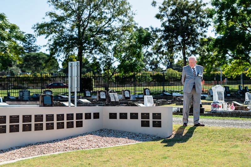 Visitor standing beside a memorial wall displaying plaques commemorating Australian service personnel.